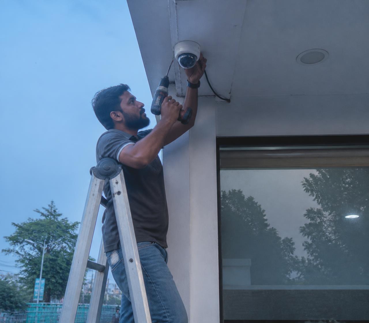 Technician installing a CCTV camera on a building in Nashik